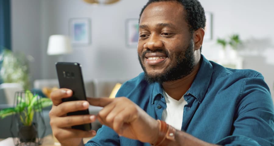 Man sitting down navigating a home security app on his smartphone